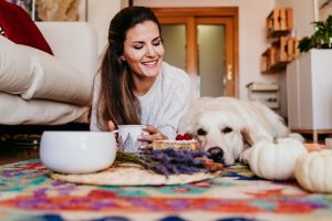 beautiful woman and cute golden retriever dog enjoying healthy breakfast at home, lying on the floor